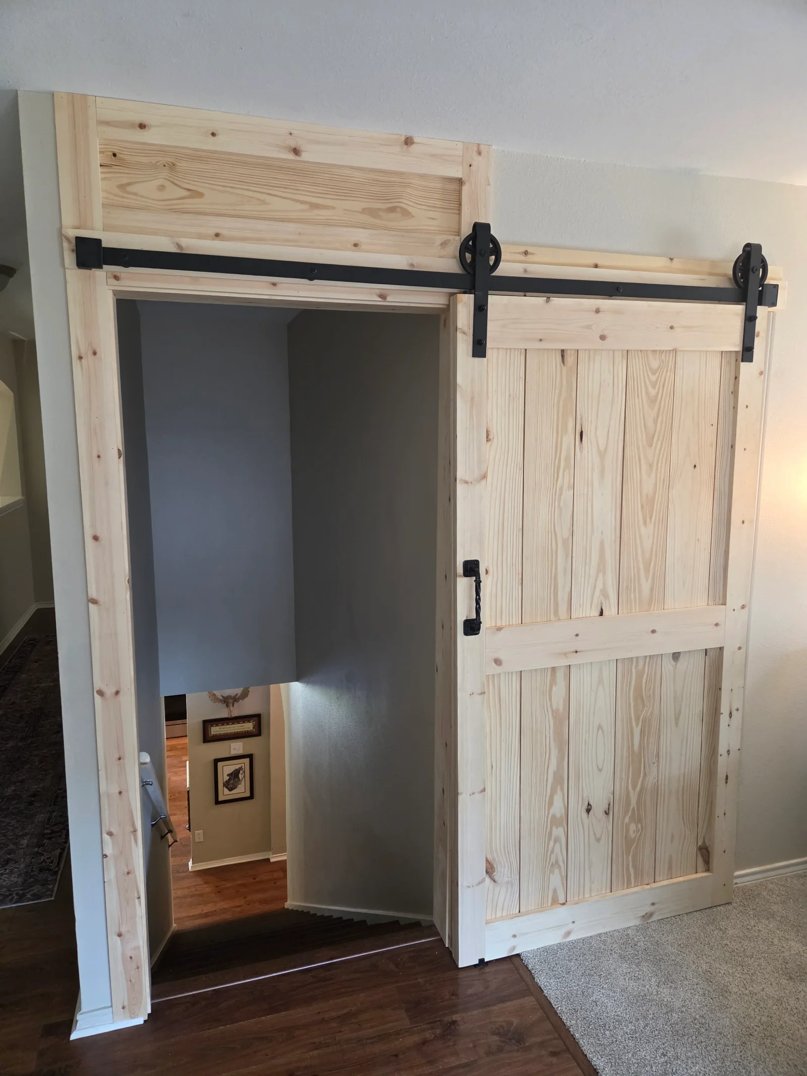 Pine barn door pantry with black sliding hardware and vertical wood paneling