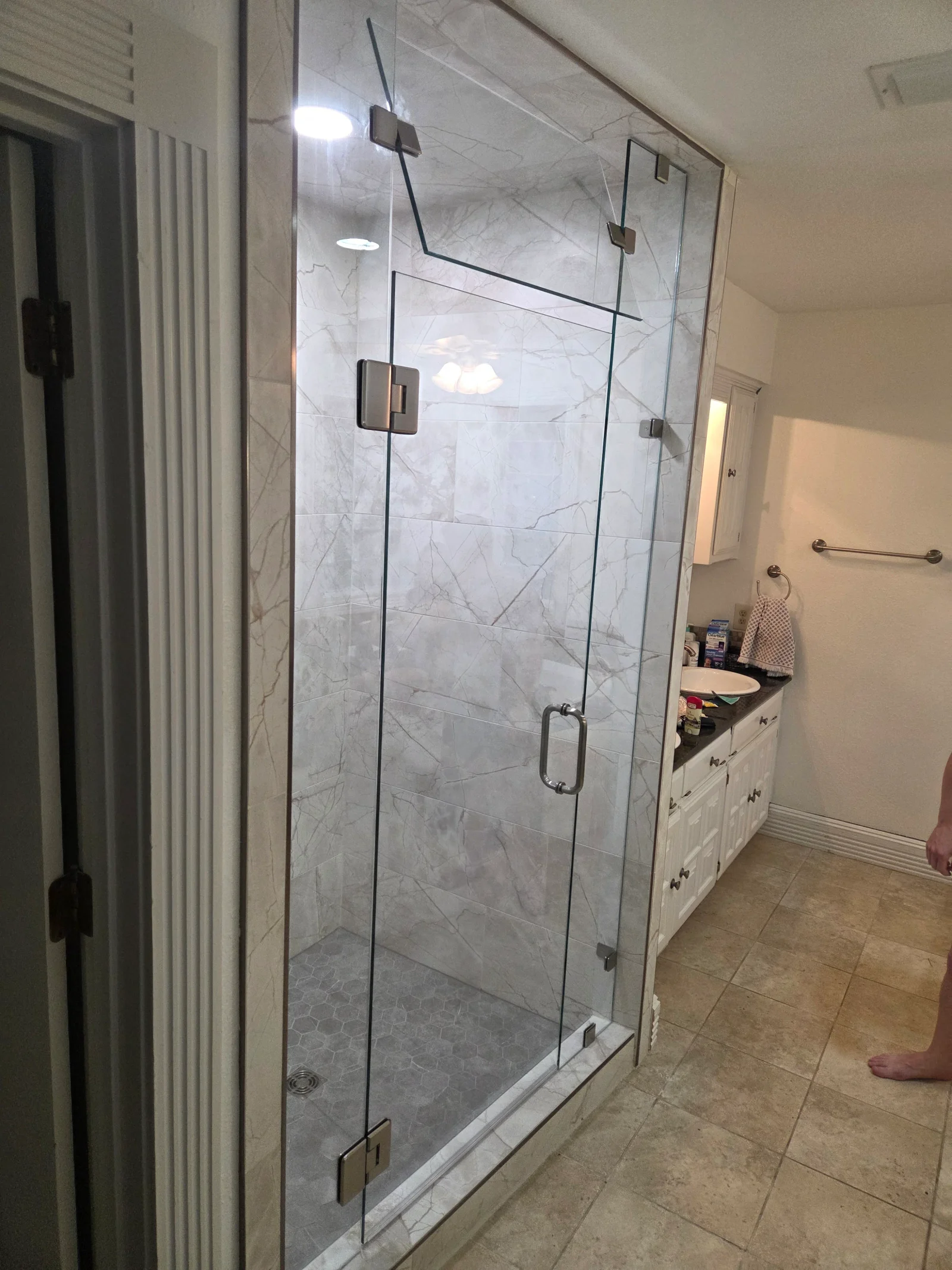 Frameless glass shower with marble tile walls and brushed nickel hardware