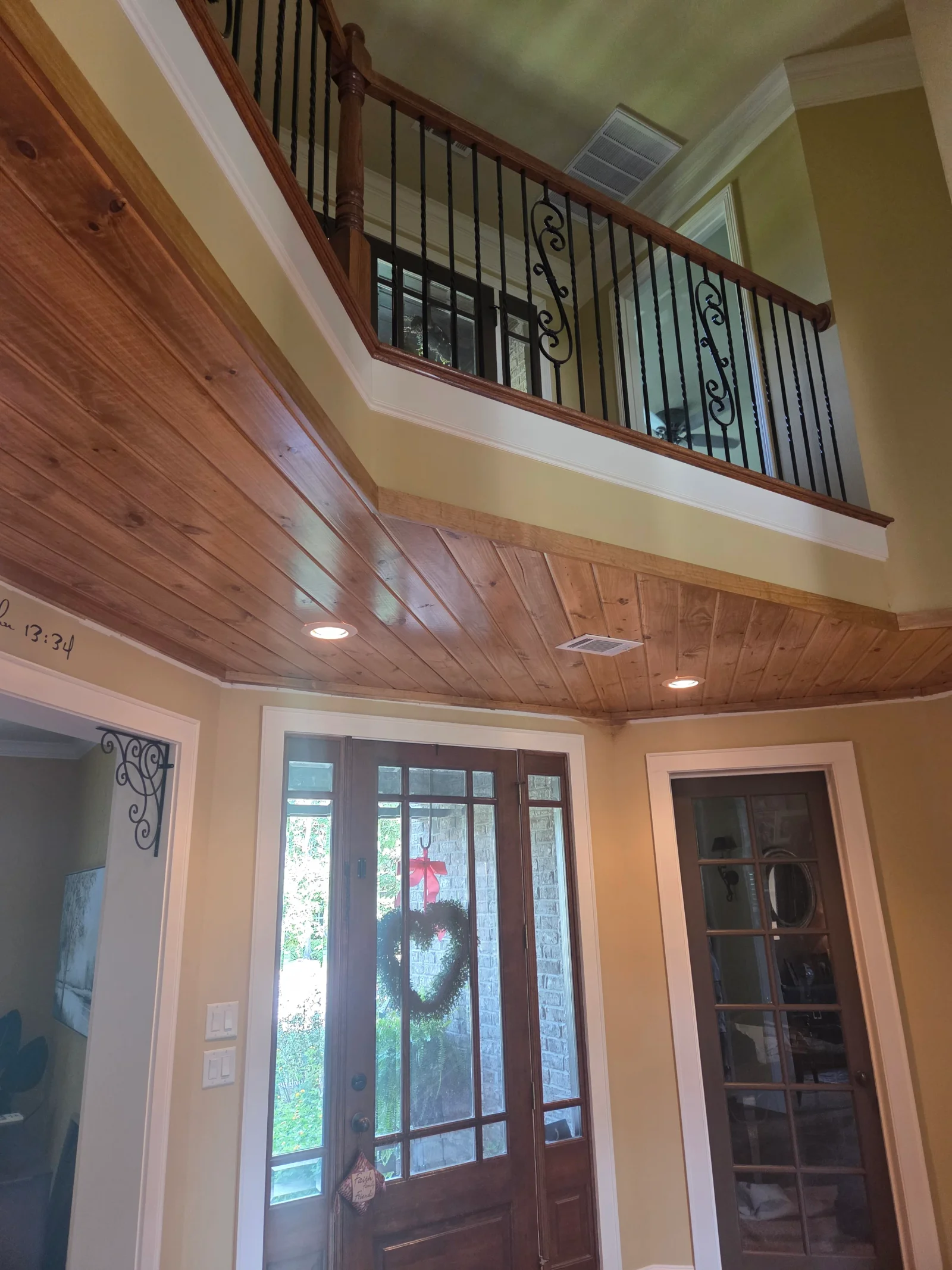 Vaulted wood soffit ceiling with recessed lights and black wrought iron railing detail