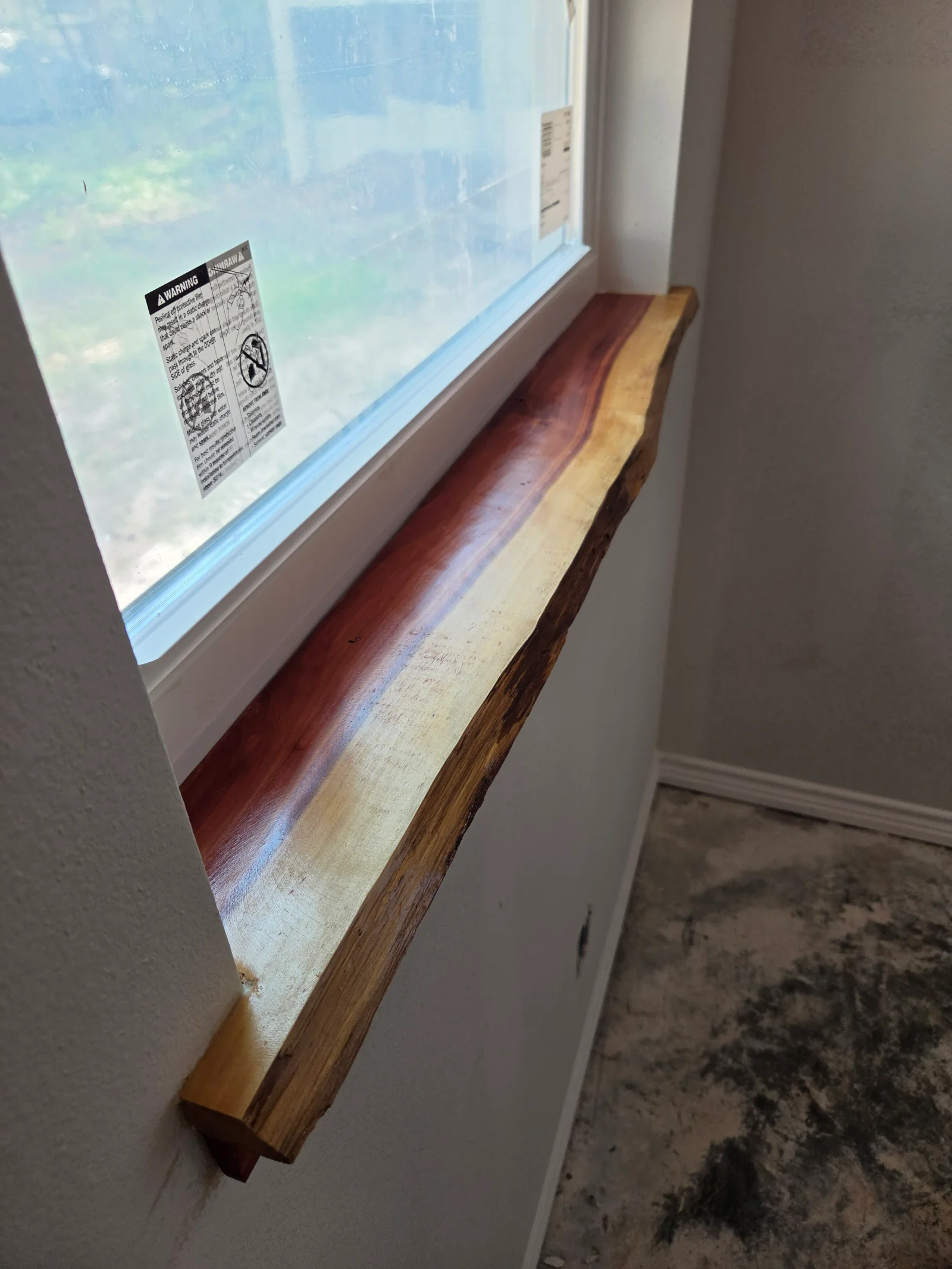 Custom hardwood window sill with mixed wood tones and natural finish beneath large window