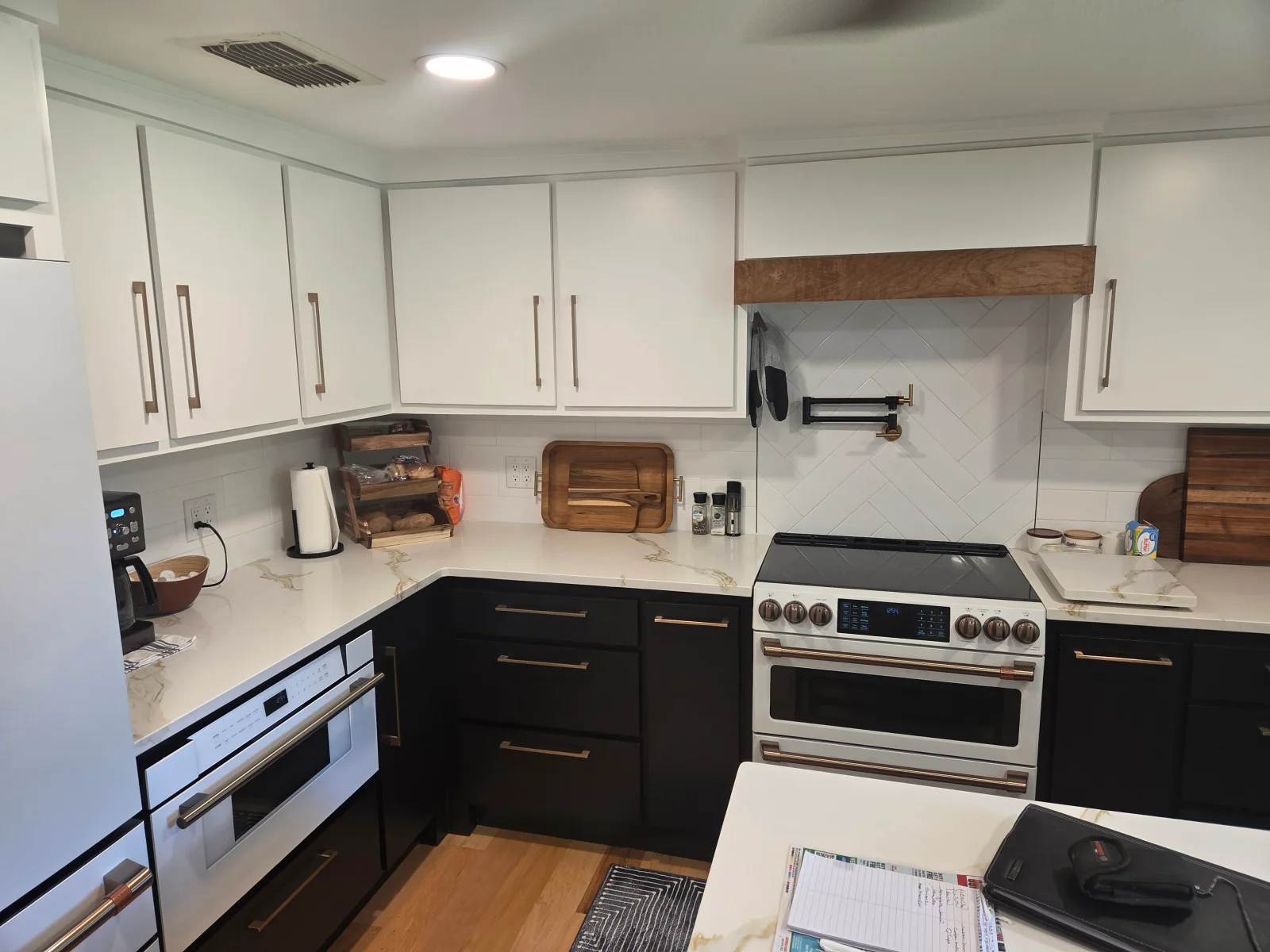 Two-tone kitchen with white upper and black lower cabinets, quartz countertop, subway tile backsplash