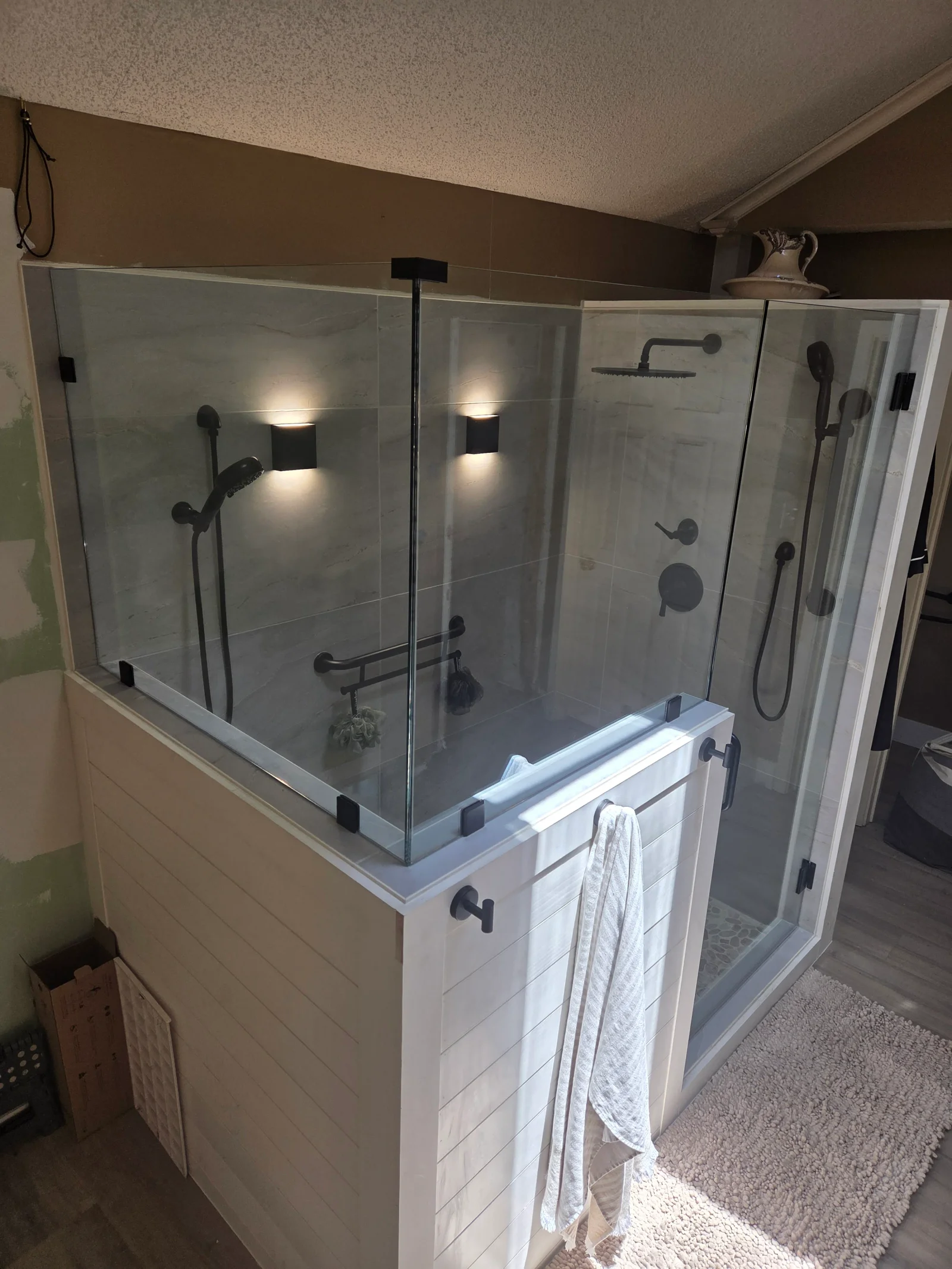 Frameless glass shower enclosure with matte black fixtures and LED lighting in white tile bathroom