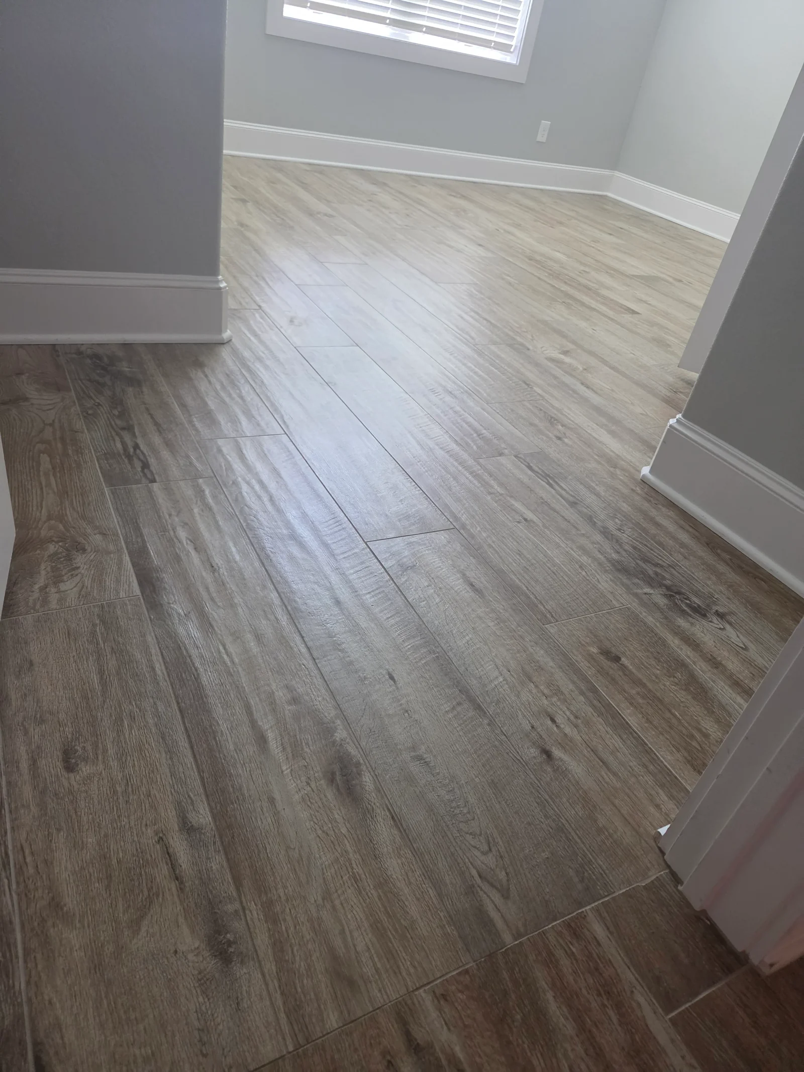 Luxury vinyl plank flooring with wood-grain pattern, white baseboards and trim throughout room
