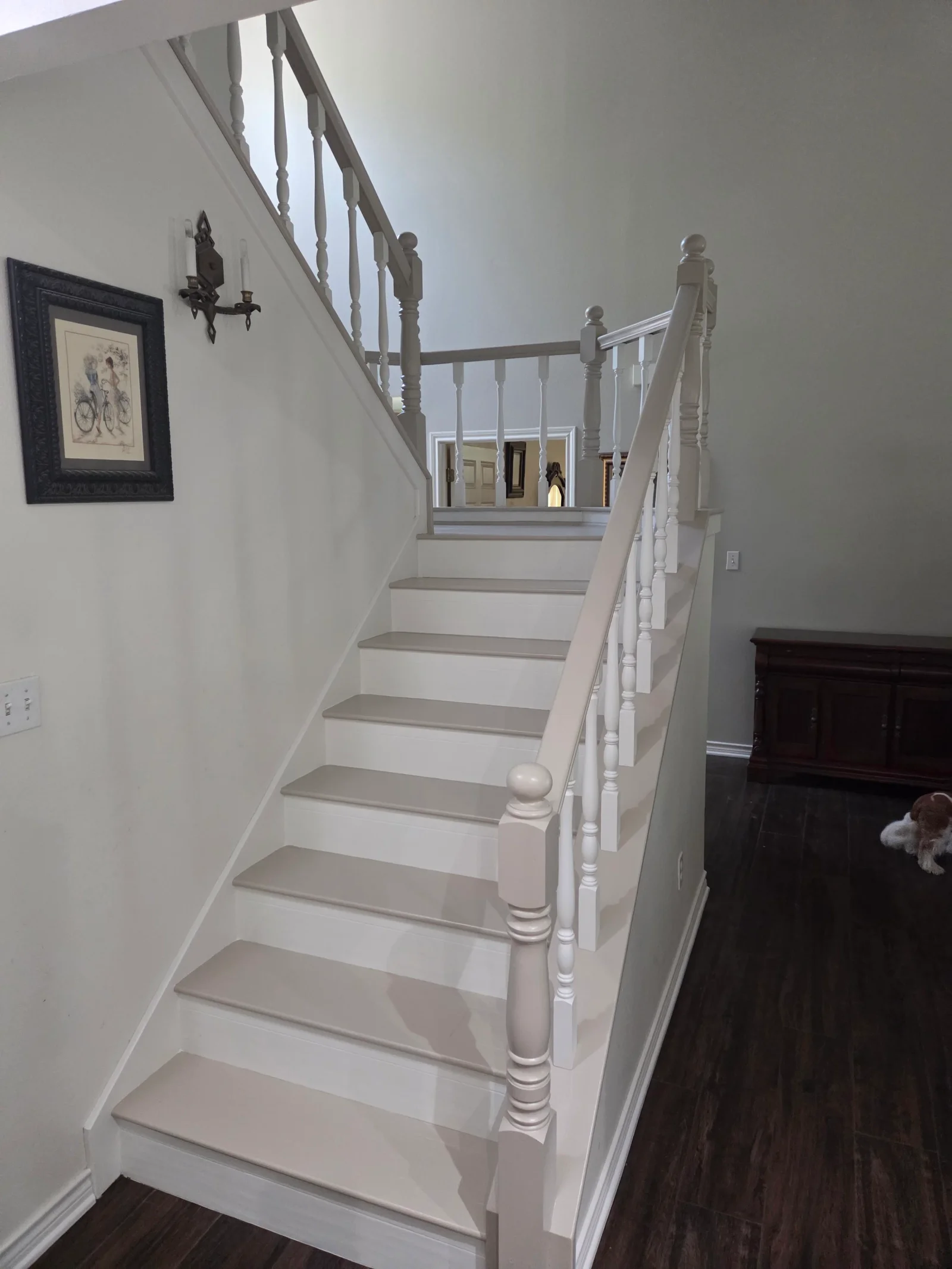 White painted staircase with turned balusters, gray treads, and white risers in residential interior