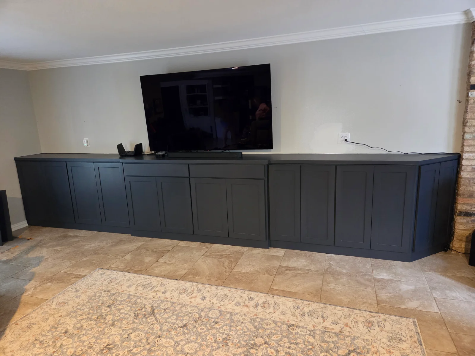 Black built-in cabinetry with recessed panels and countertop, TV mounted above